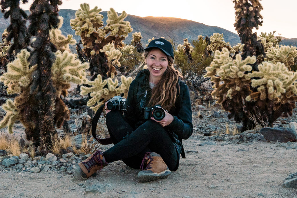 photographer sitting in cactus garden holding cameras