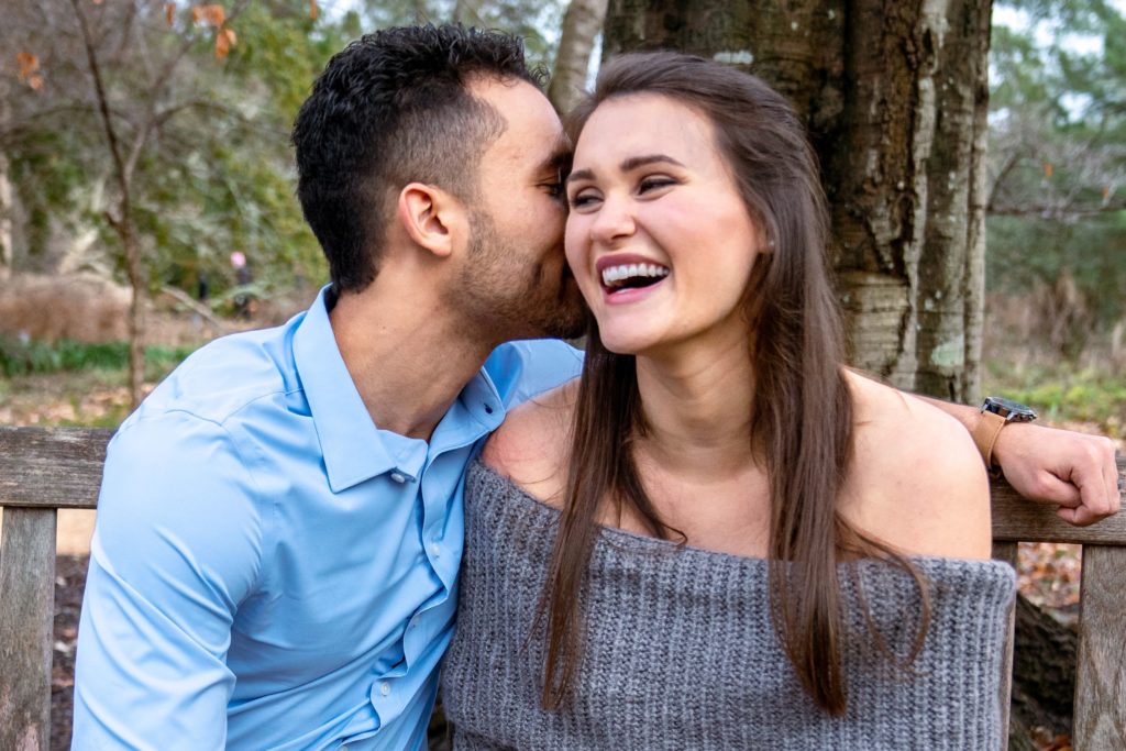 wife laughing as husband whispers into her ear