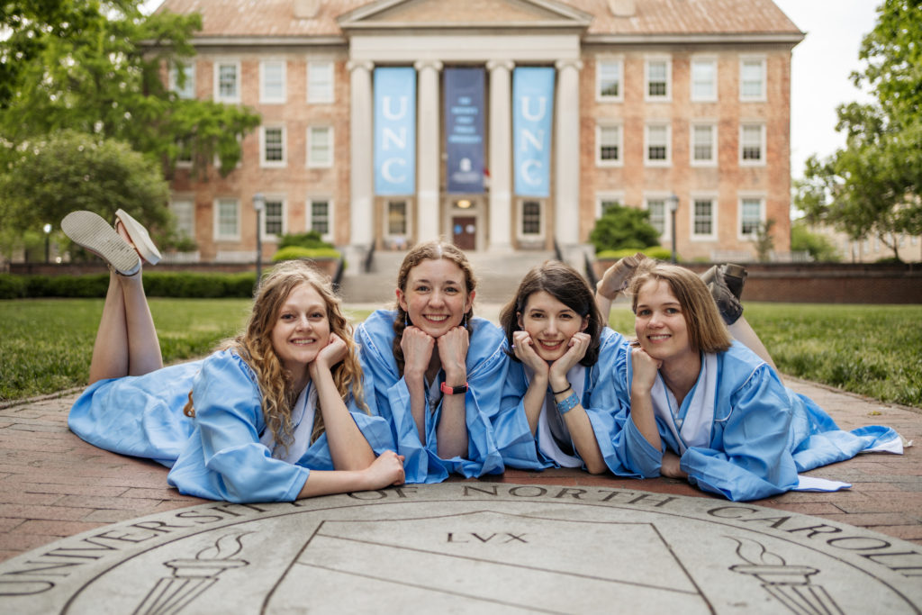 Four UNC students lying down by the UNC seal in front of South Building