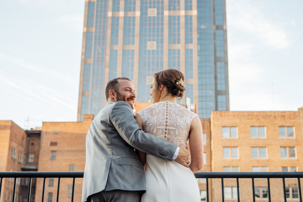 bride and groom stand in front of skyline