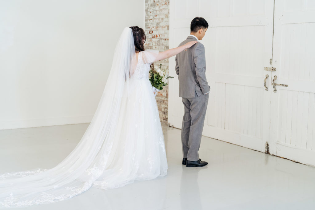 bride taps groom on the shoulder during first look