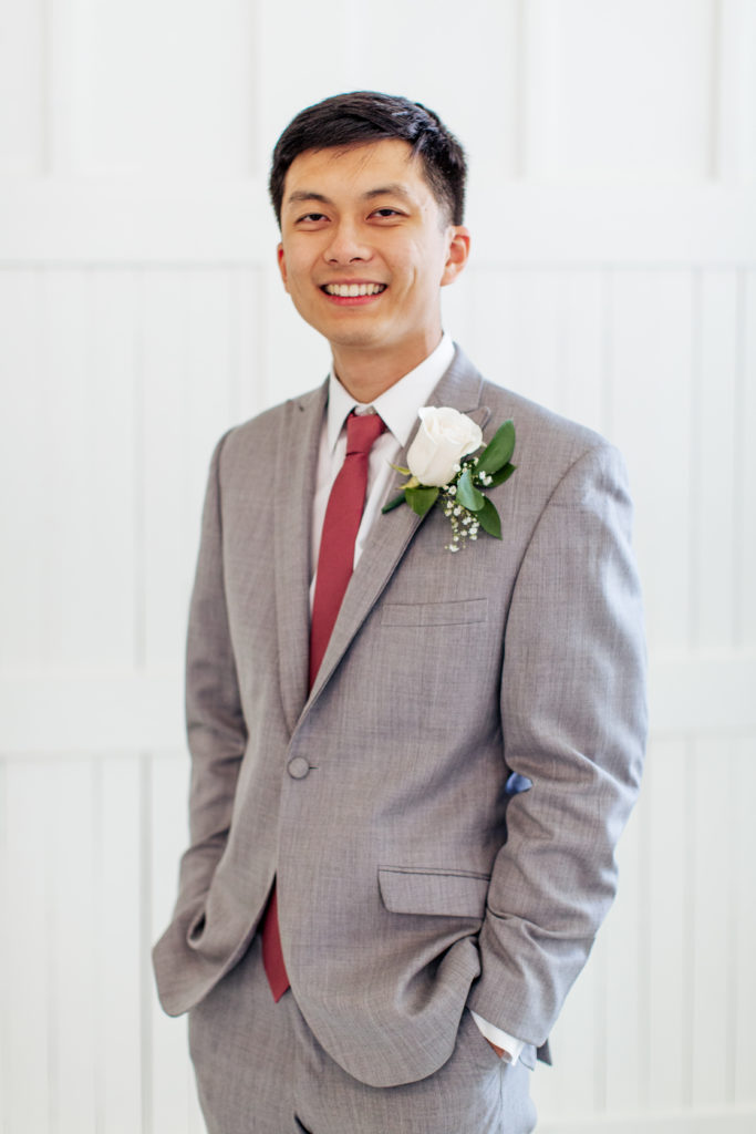 groom smiling and standing in front of white barn doors