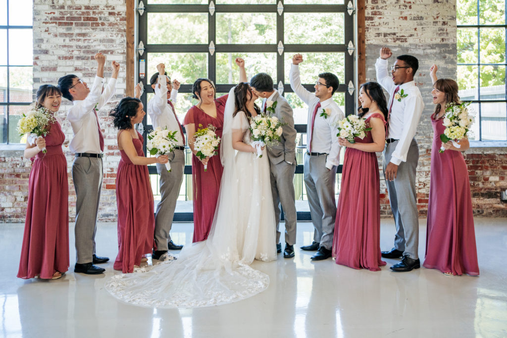 bride and groom kiss while bridesmaids and groomsmen cheer