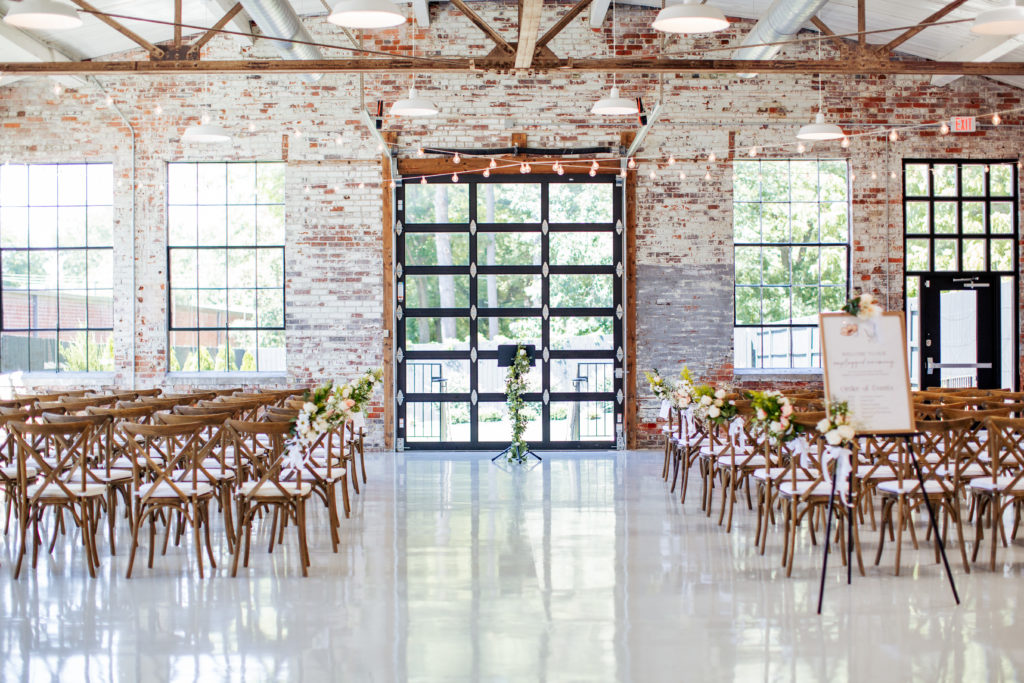 wedding ceremony set up in front of garage door and brick wall with many windows