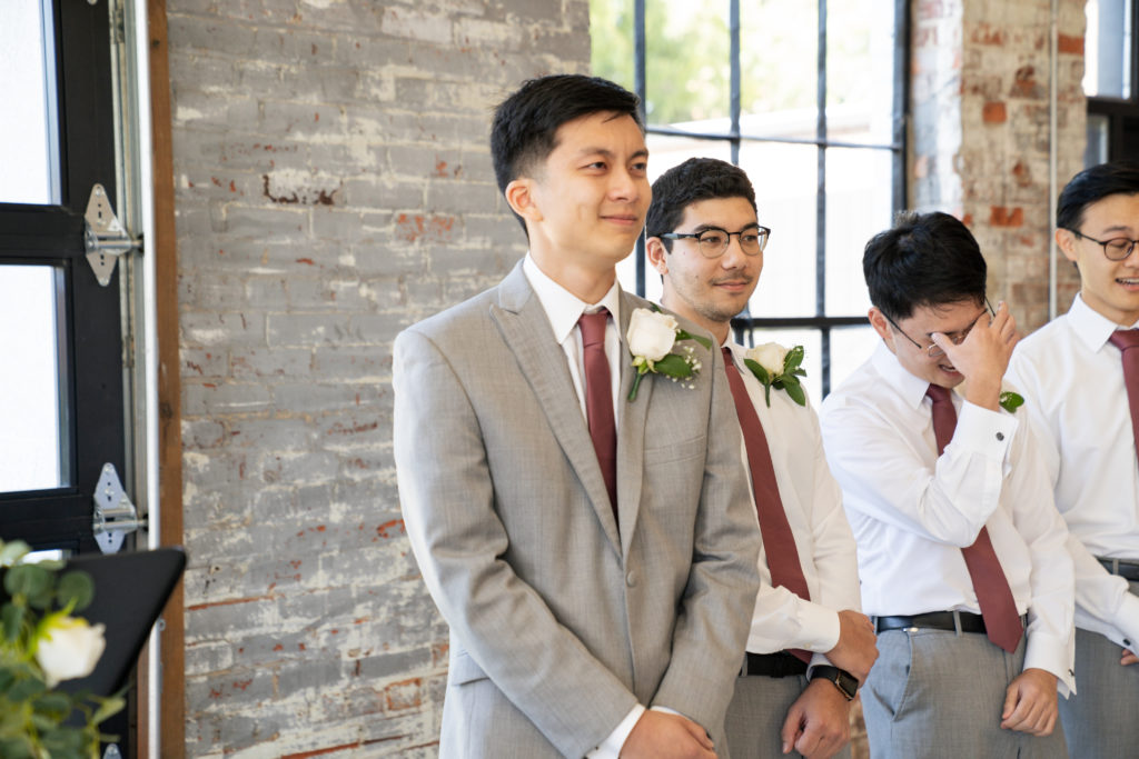 groom smiling and crying when he sees his bride
