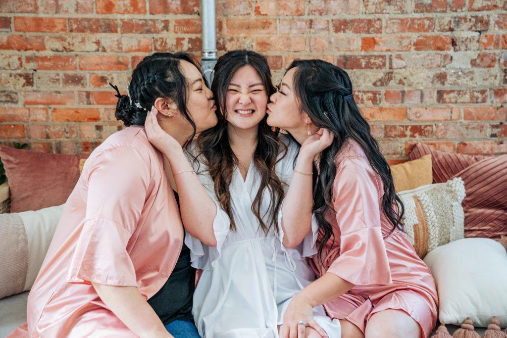 bride kissed on cheek by her maids of honor