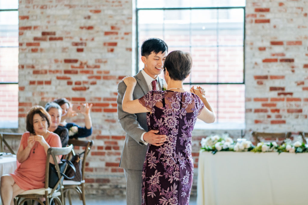 mother son dance during wedding with brick wall and windows