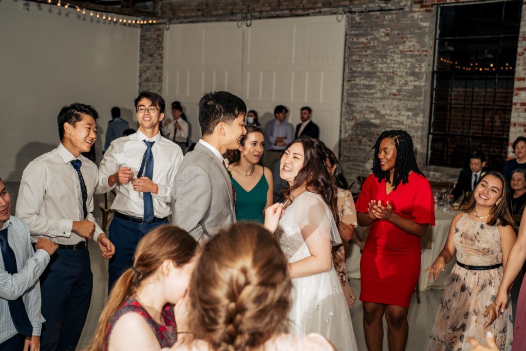bride and groom dance surrounded by friends