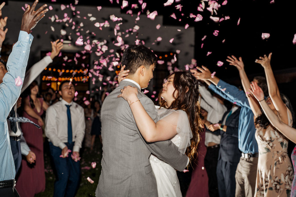 bride and groom hold each other close during flower petal exit