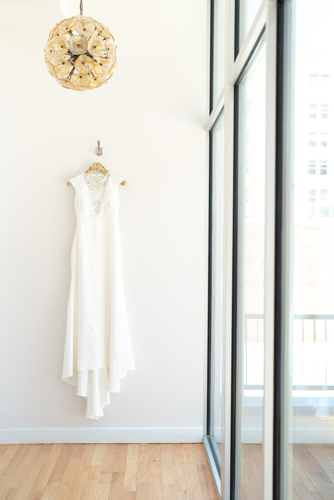 wedding dress hung on wall next to a window