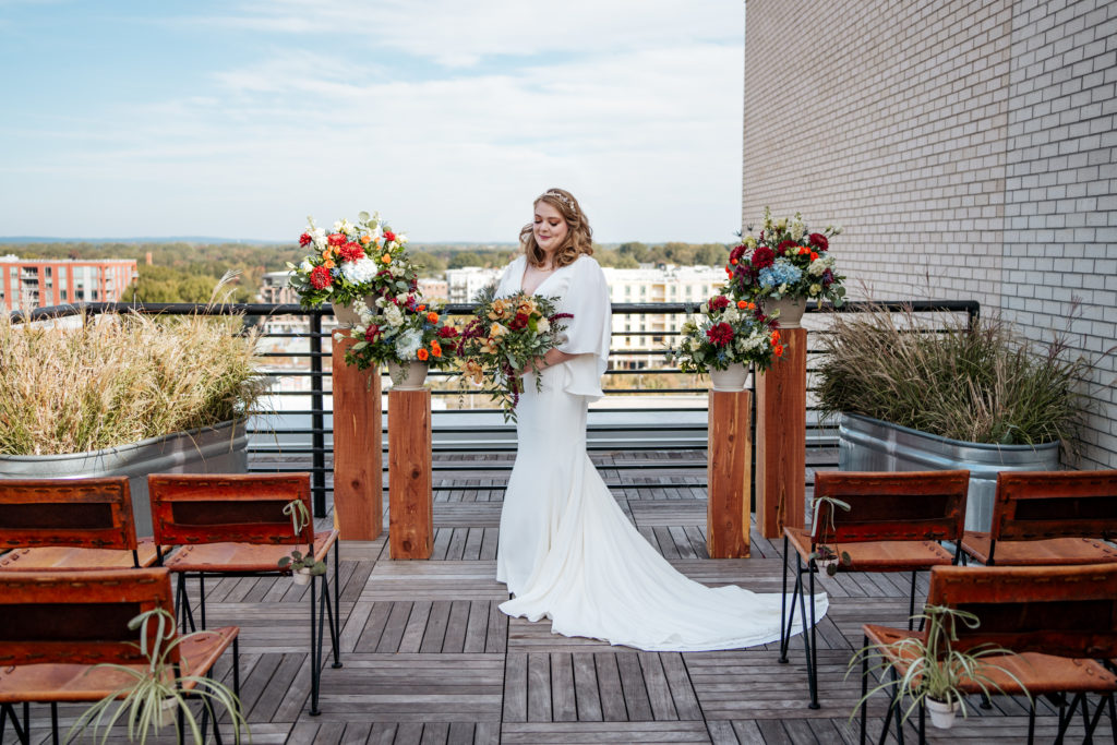 bride looks at her bouquet on the rooftop of the Durham Hotel