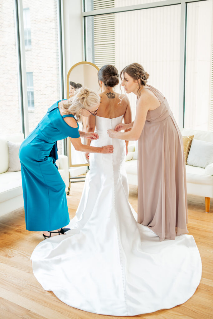 mother and sister help bride into her dress at the Glass Box in Raleigh, NC