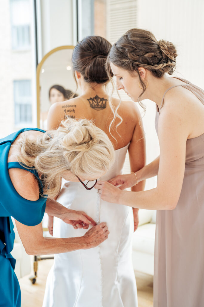 mother and sister help bride into her dress at the Glass Box in Raleigh, NC