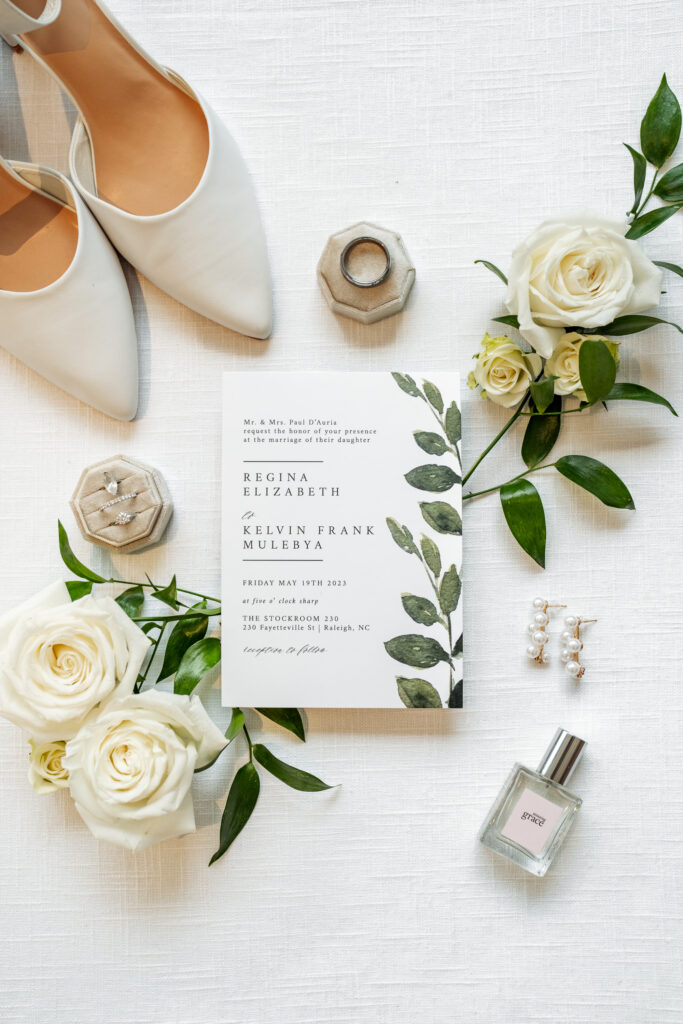 wedding invitation flat lay with white roses and greenery