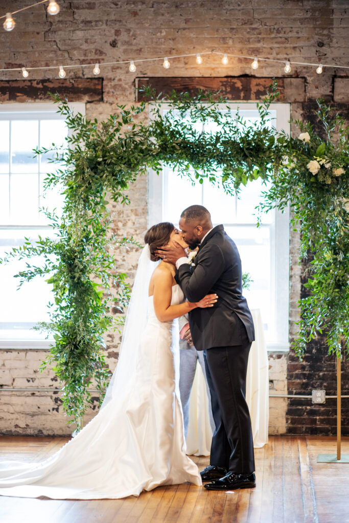 bride and groom kiss at wedding ceremony at the Stockroom at 230 wedding in downtown Raleigh, NC