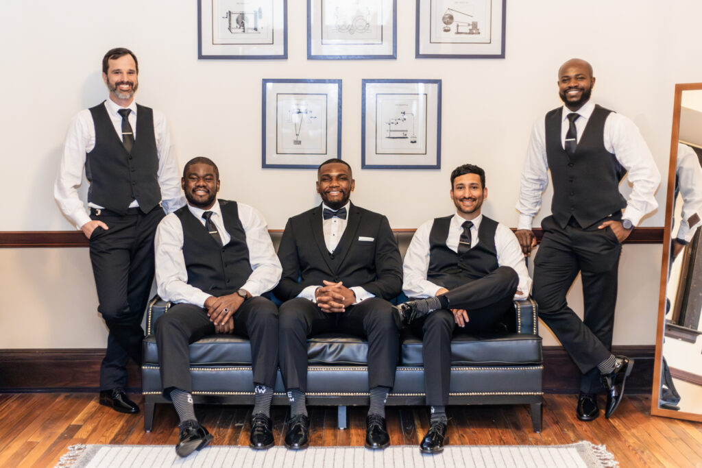groom and groomsmen smile in the lounge of the stockroom at 230