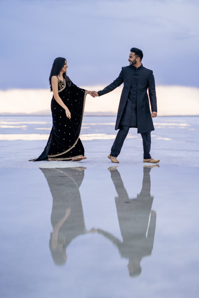 Engagement photos at the Bonneville Salt Flats with reflective water pools at sunrise
