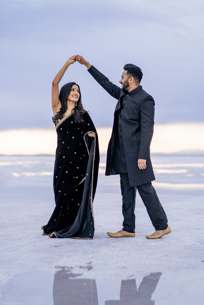 Couple wears Indian clothing during Bonneville Salt Flats engagement photos with reflective water at sunrise