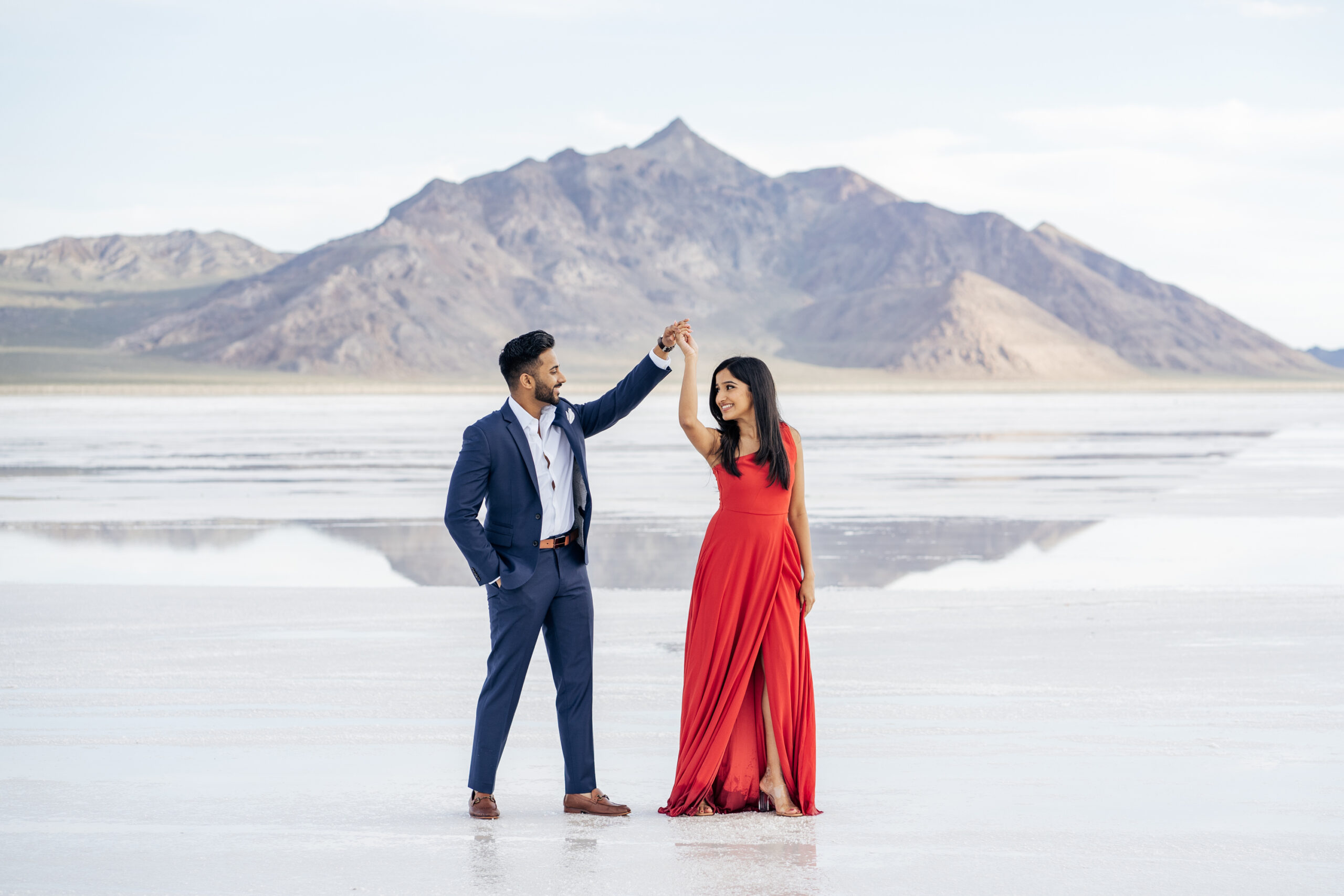 Engagement photos at the Bonneville Salt Flats with mountain in distance and water reflections on the ground.