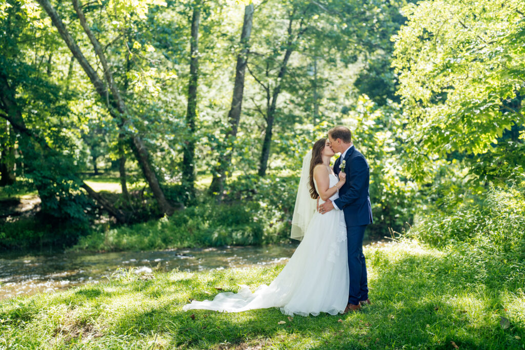 Bride and groom kiss by a river in Boone, NC