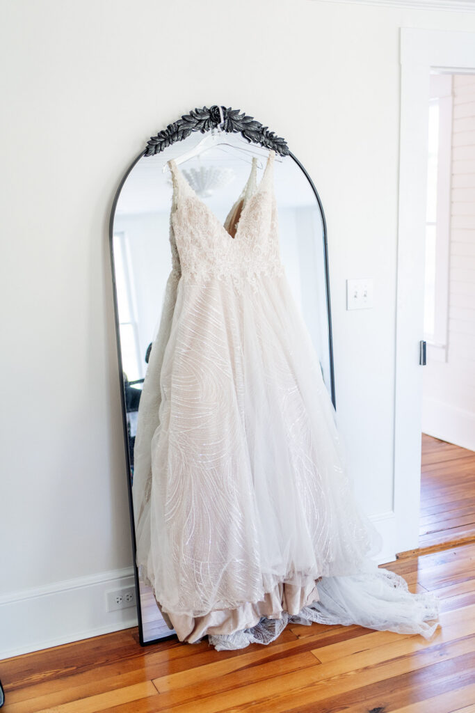 wedding dress hangs on mirror in the bridal suite of the Upchurch wedding venue in Cary, NC