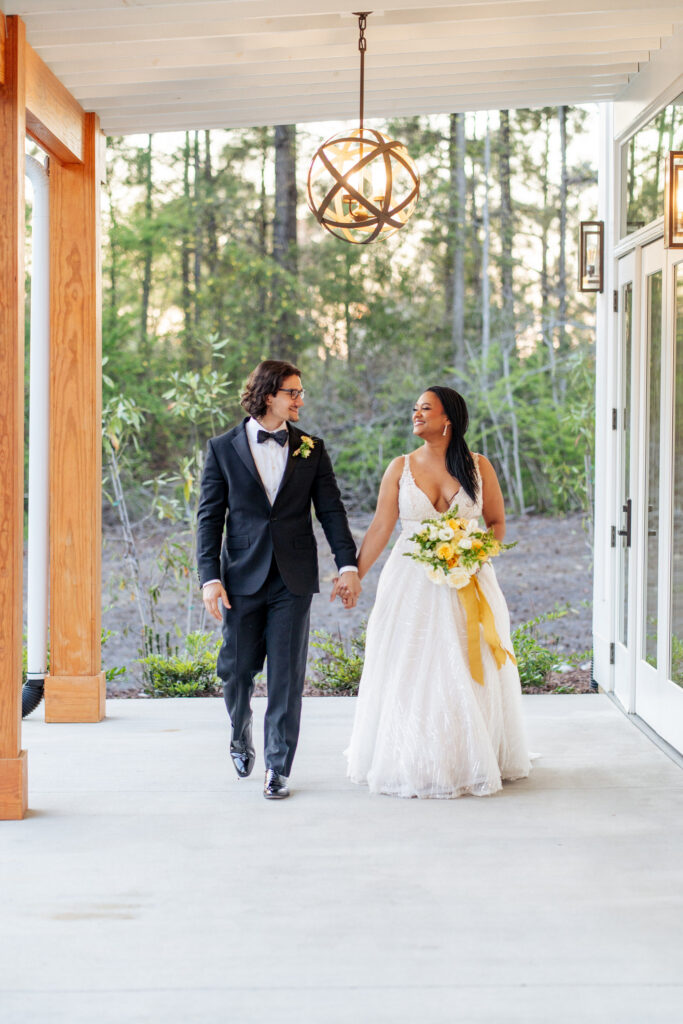 bride and groom hold hands and walk at wedding at the Upchurch on patio
