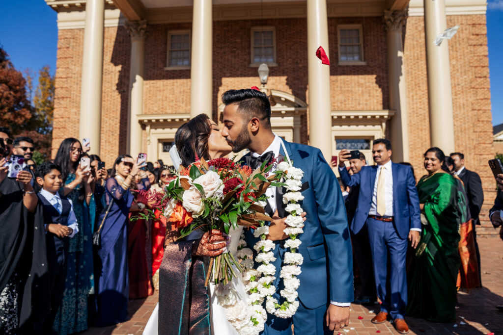 bride and groom kiss during rose petal send off at Hayes Barton Baptist wedding
