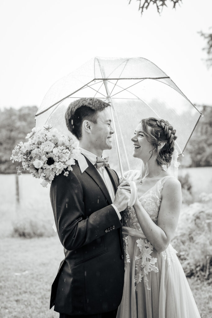 Bride and groom hold an umbrella in the rain