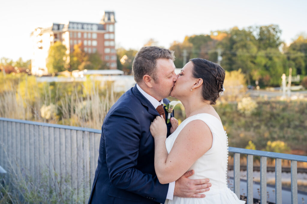 bride and groom kiss on the terrace at Union Hall at Raleigh Union Station