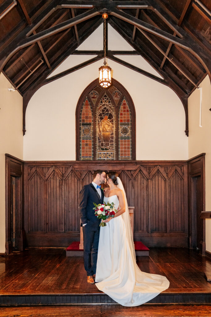 bride and groom kiss at All Saints Chapel in Raleigh, NC
