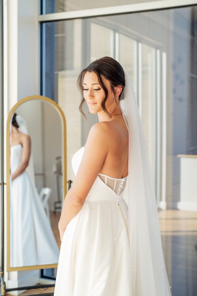 Bride looking over her shoulder in front of the mirror at the Glass Box in downtown Raleigh, NC