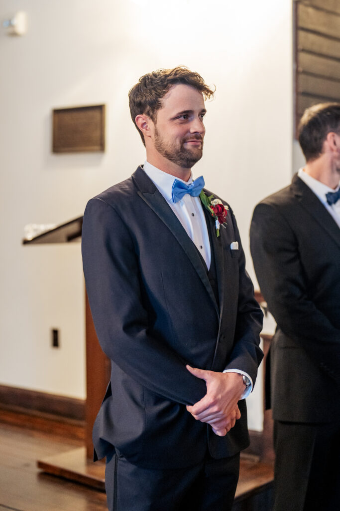 groom sees bride walking down the aisle at wedding ceremony in All Saints Chapel