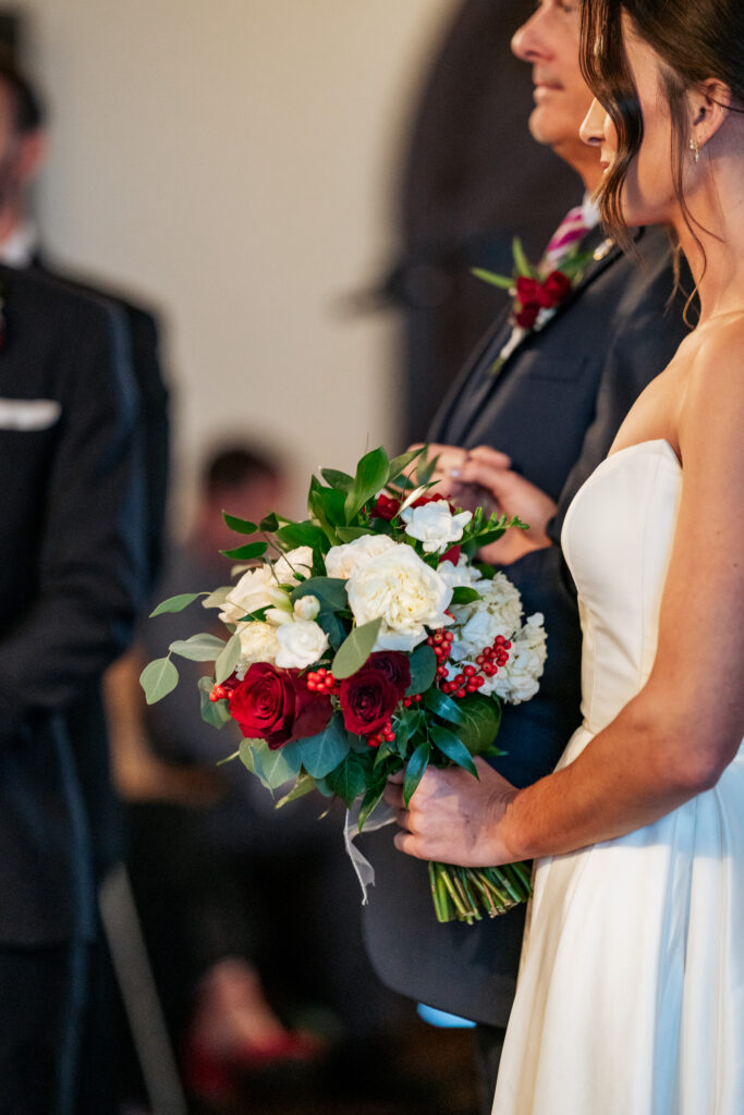 bride holding a bouquet of red and white flowers