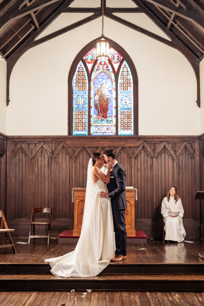 first kiss at wedding ceremony at All Saints Chapel in downtown Raleigh