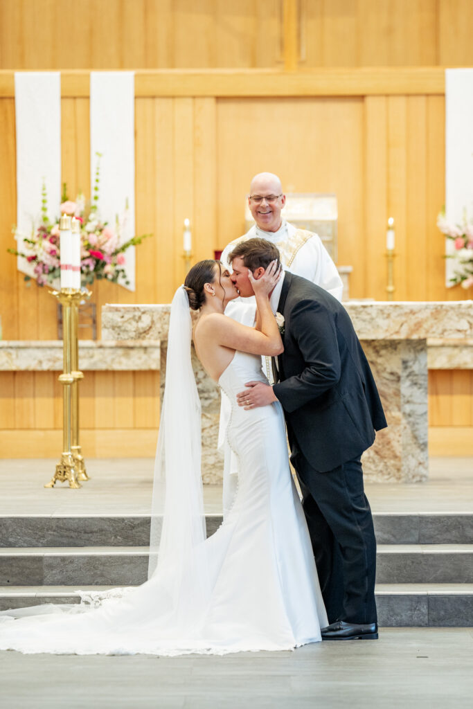 bride and groom first kiss at St. Mary Magdalene Catholic Church in Apex