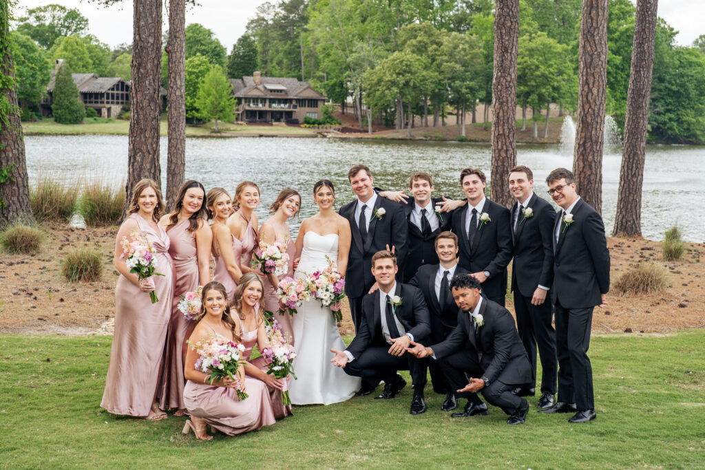 wedding party poses in front of lake at MacGregor Downs Country Club