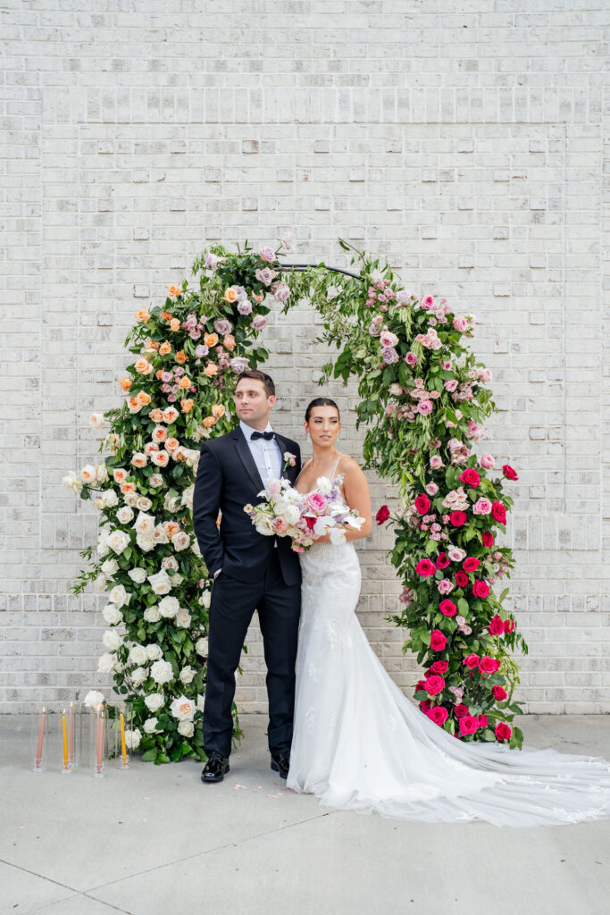 bride and groom pose for portrait in front of floral ceremony arch at the Maxwell