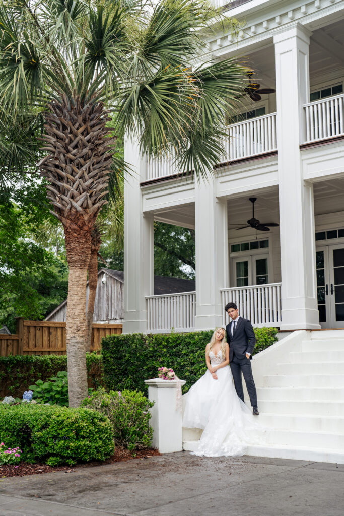 bride and groom pose for picture in front of Southern coastal home in Wilmington, NC