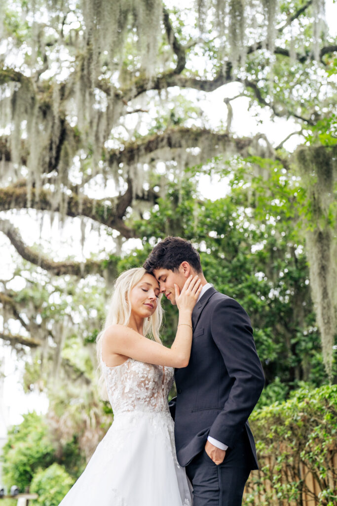 Bride and groom embrace under Spanish moss in Wilmington, NC