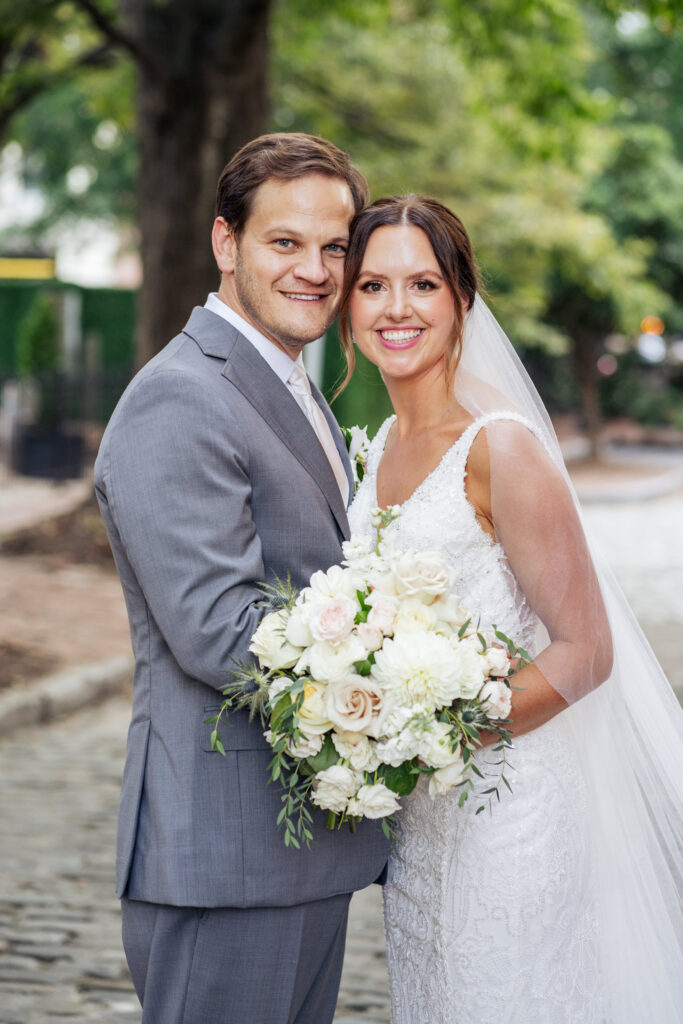 bride and groom smile for picture outside Market Hall in Downtown Raleigh