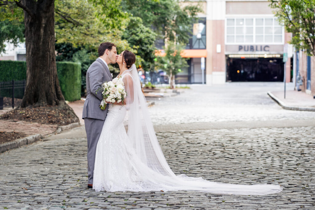 bride and groom kiss outside Historic Market Hall in downtown Raleigh