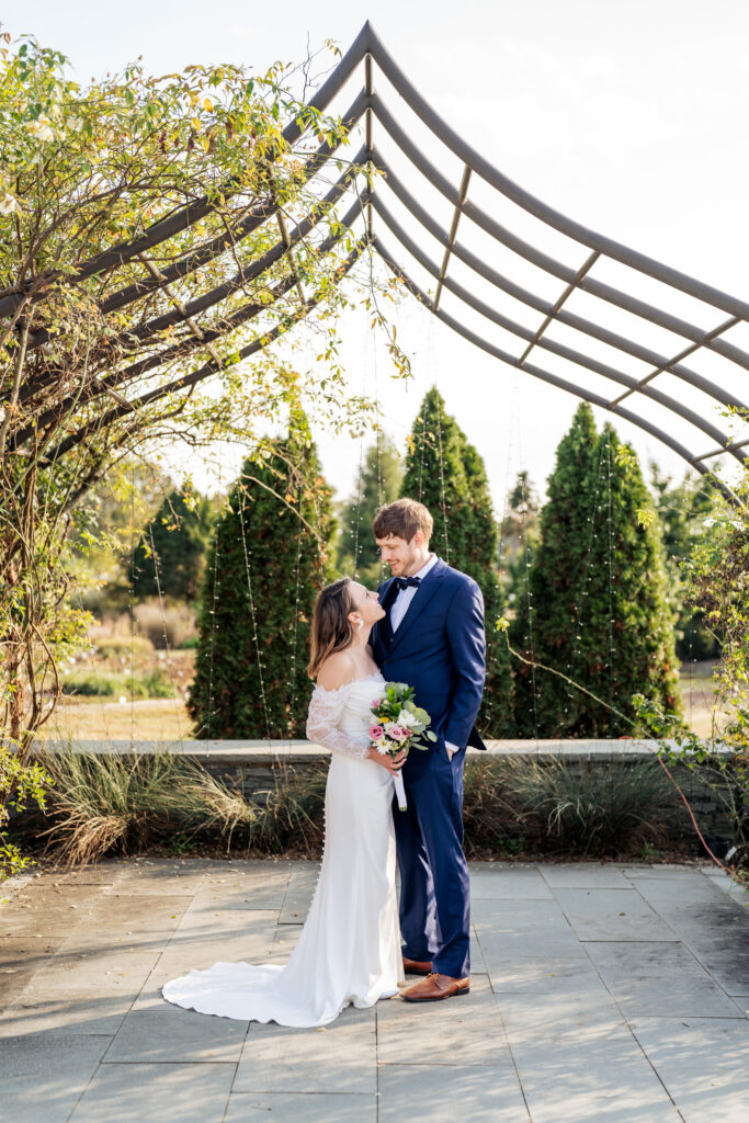 bride and groom stand in rose garden at JC Raulston for ceremony