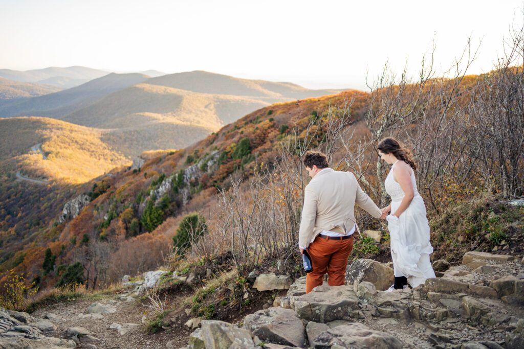 Bride and groom holding hands walking over rocks at Stony Man Mountain