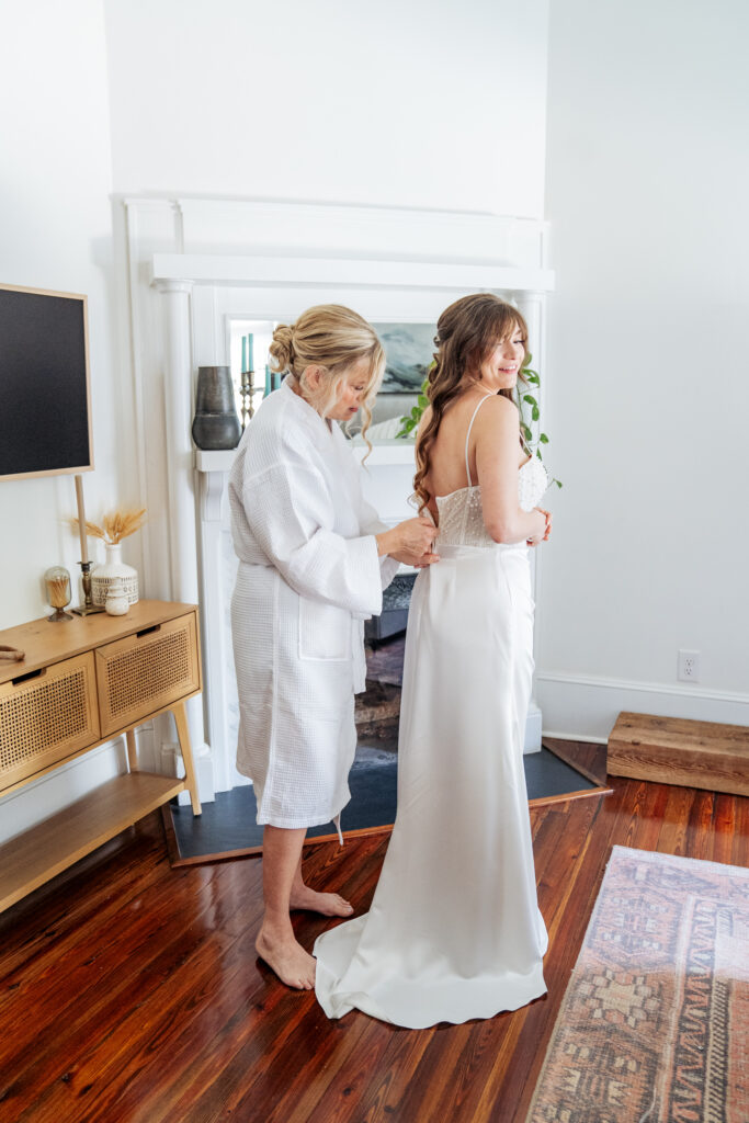 mother zipping up bride's dress