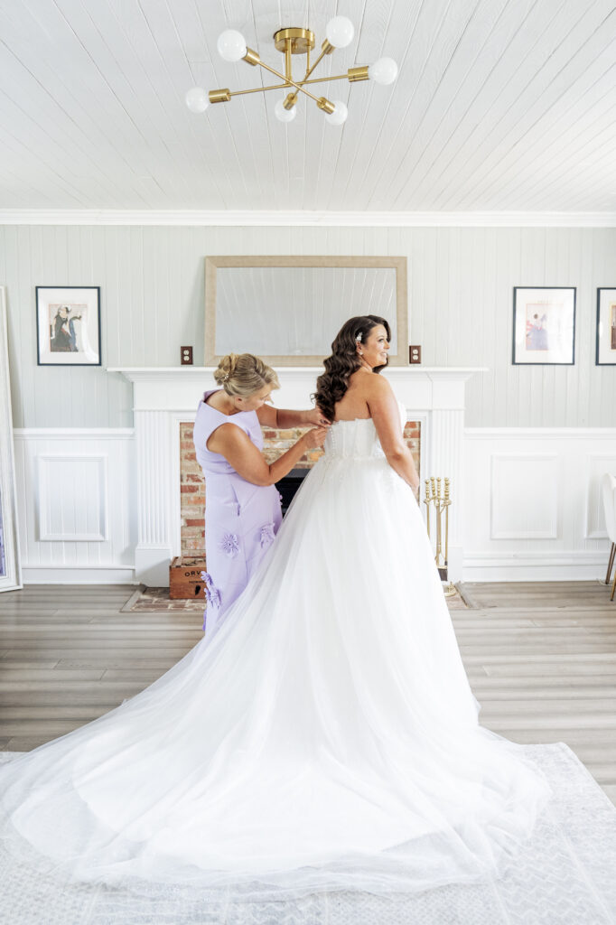 mother of bride zipping up bride's dress in the bridal suite at Historic Wakefield Barn