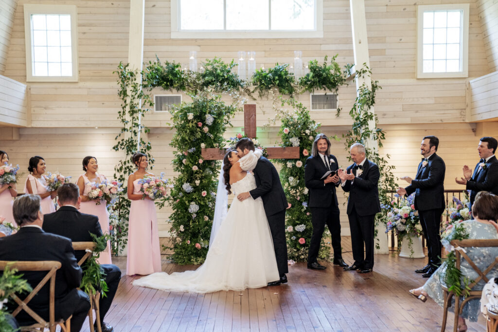 bride and groom first kiss at indoor wedding ceremony at Historic Wakefield Barn
