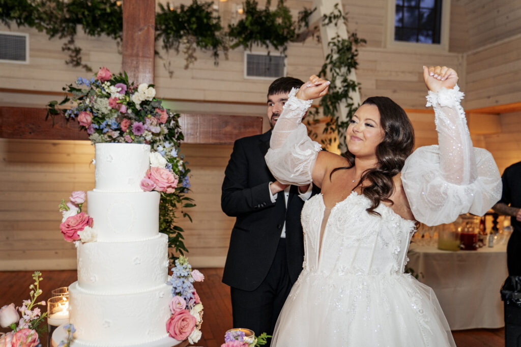 bride cheers after cutting cake at Historic Wakefield Barn