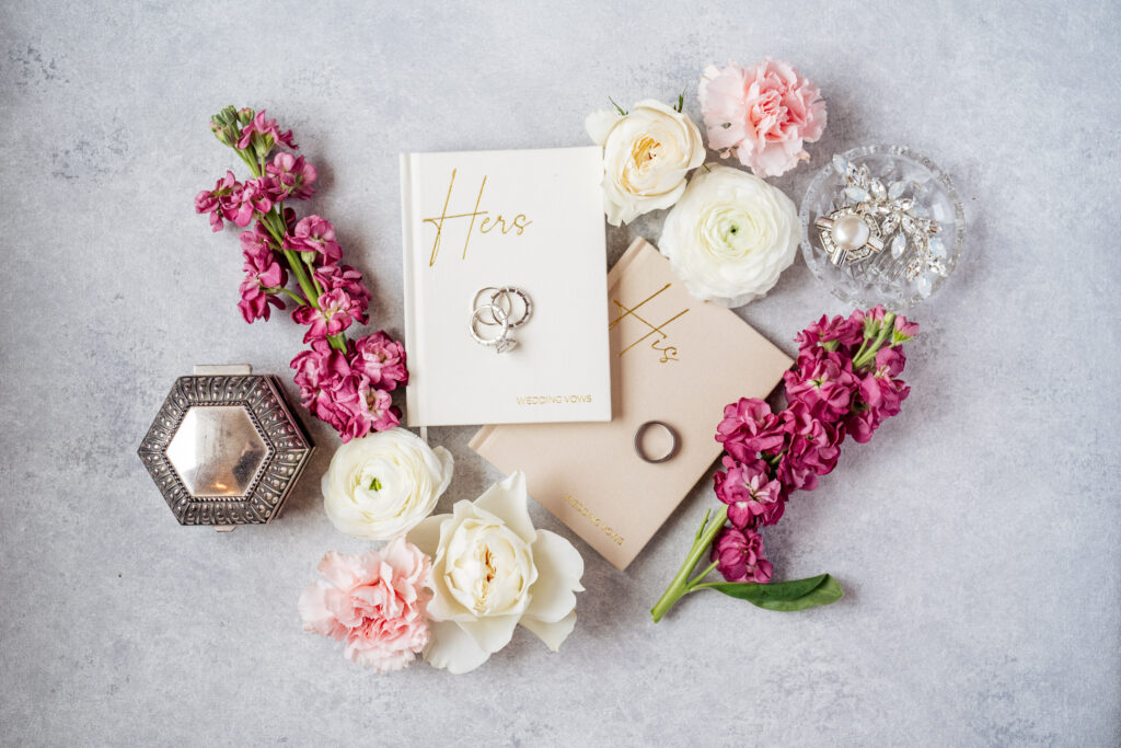 vow books with rings and florals in wedding flat lay