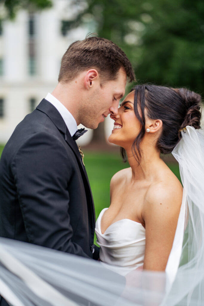 bride and groom smiling for portrait on the lawn of the Capitol building in Raleigh, NC