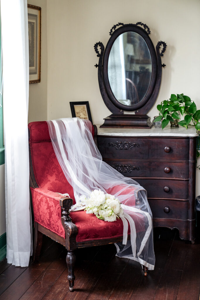 bridal bouquet and veil draped across a red armchair at Haywood Hall in downtown Raleigh